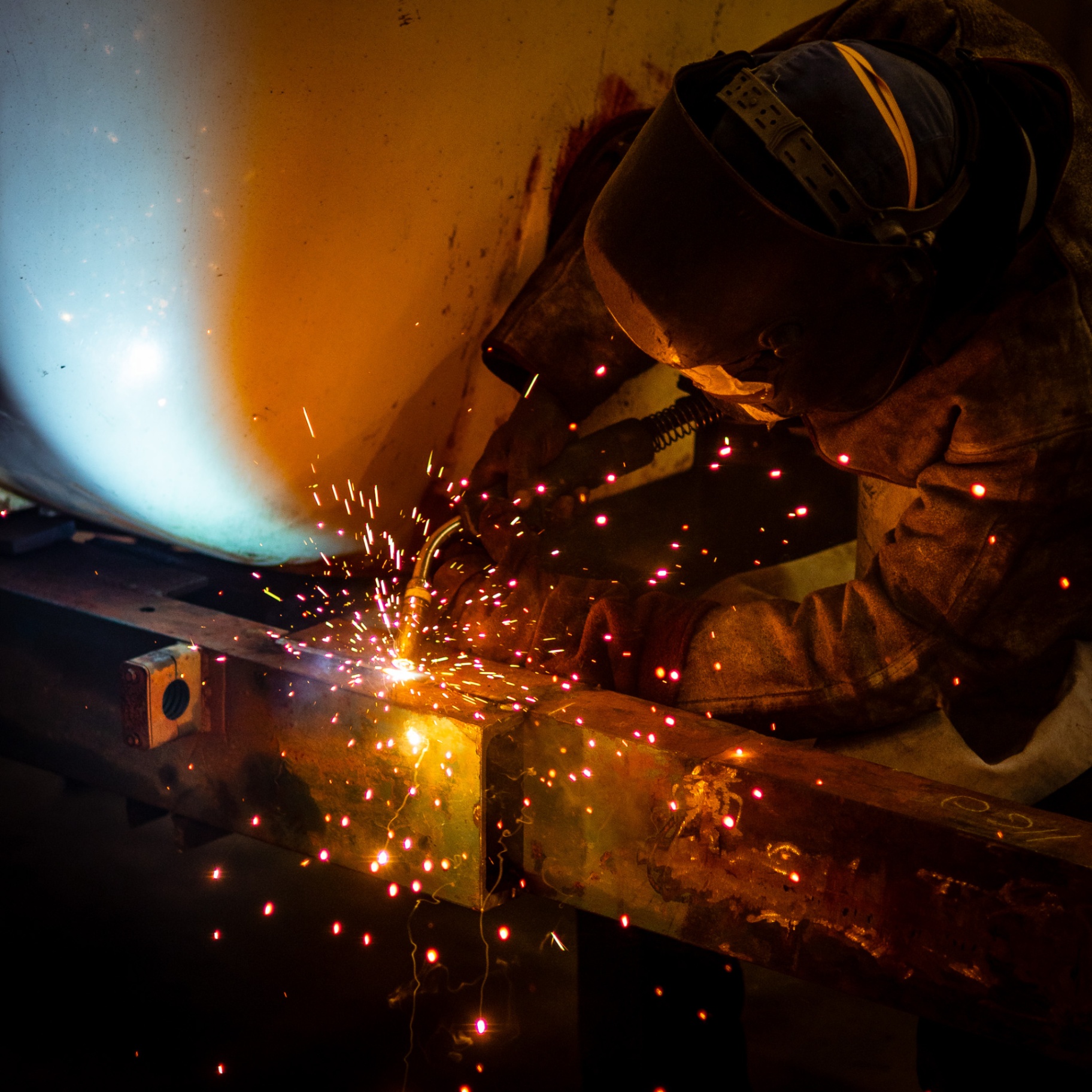 MIG welder fabricating a steel frame with sparks flying
