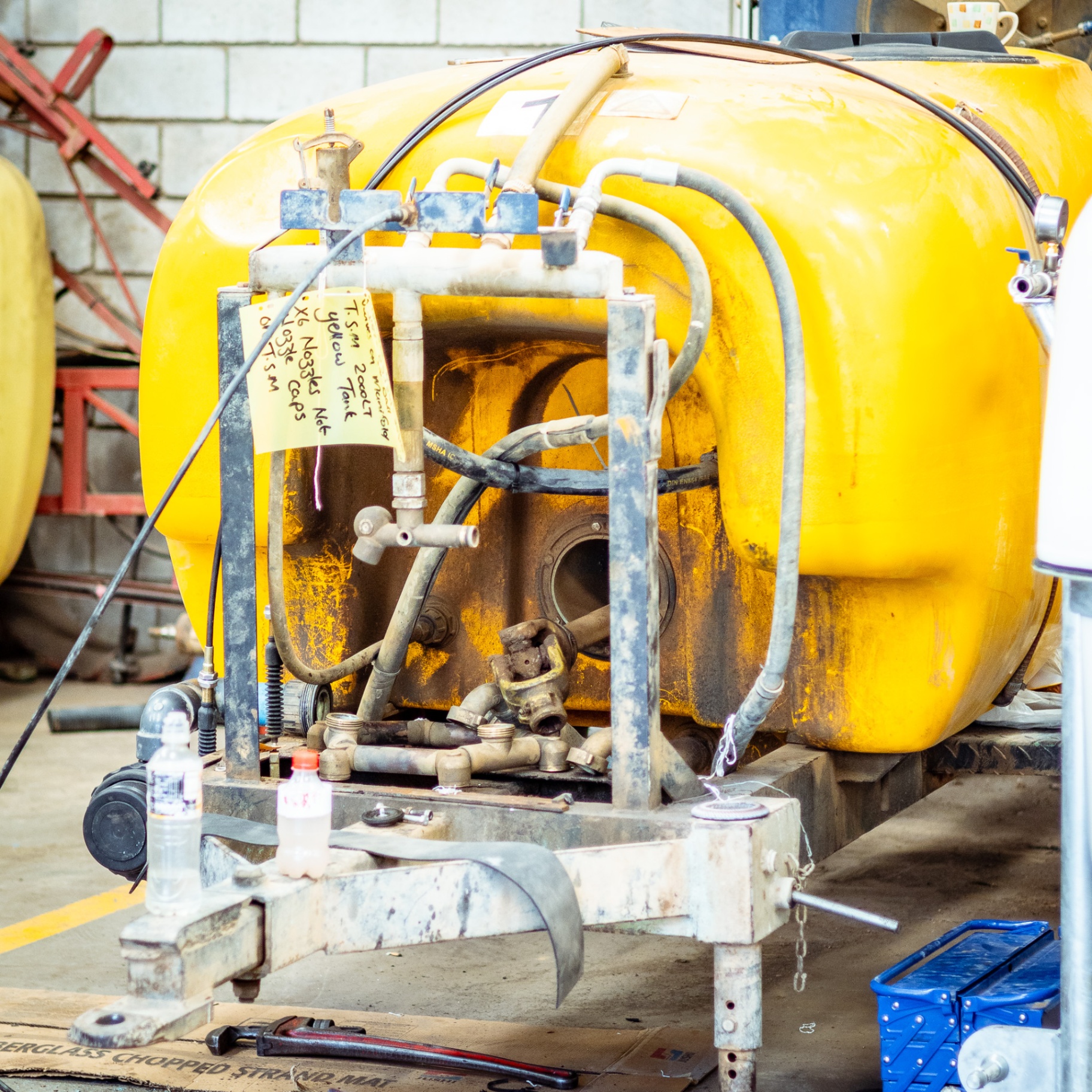 Yellow agricultural tank trailer undergoing maintenance in the workshop