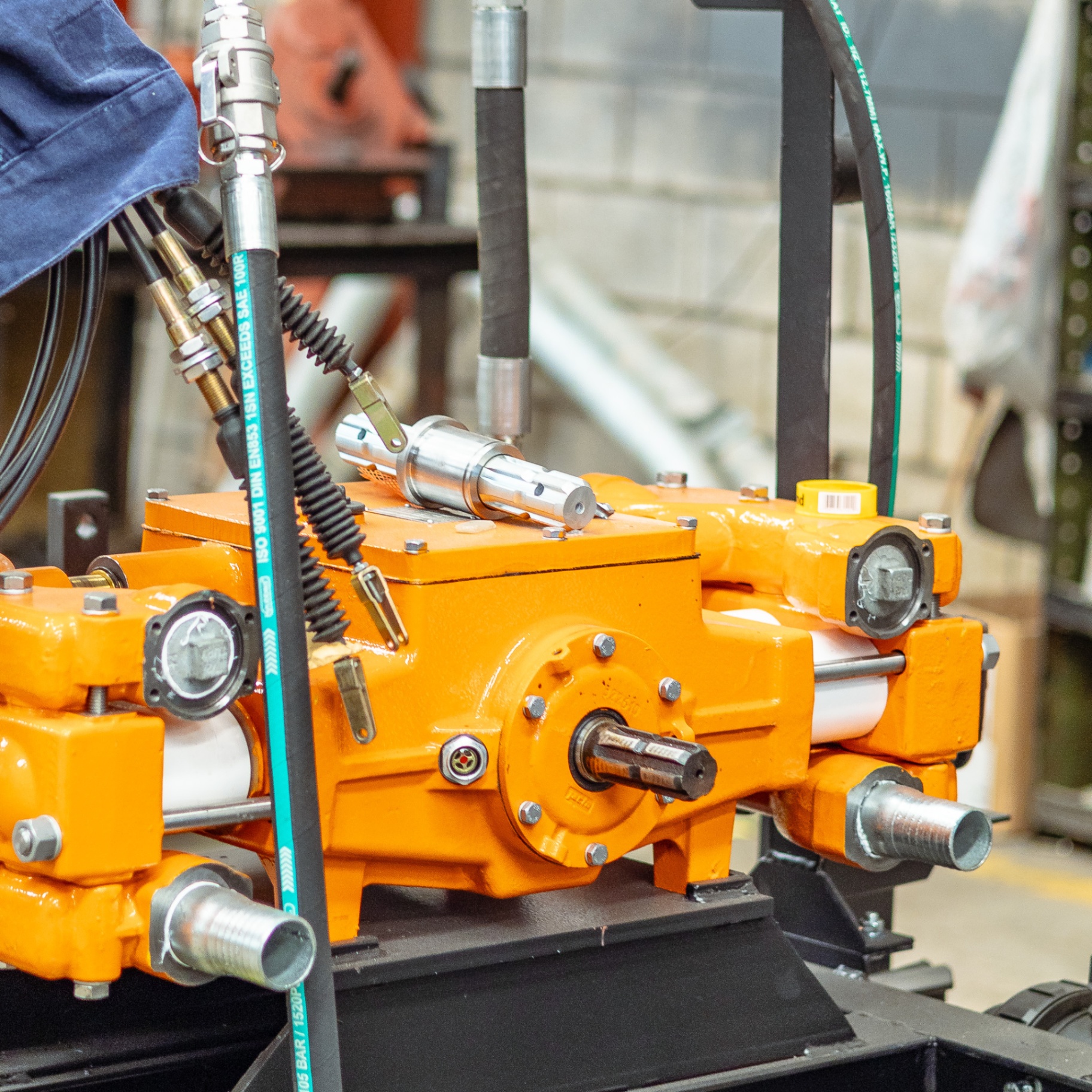 Close-up of bright orange hydraulic machinery on a workshop bench