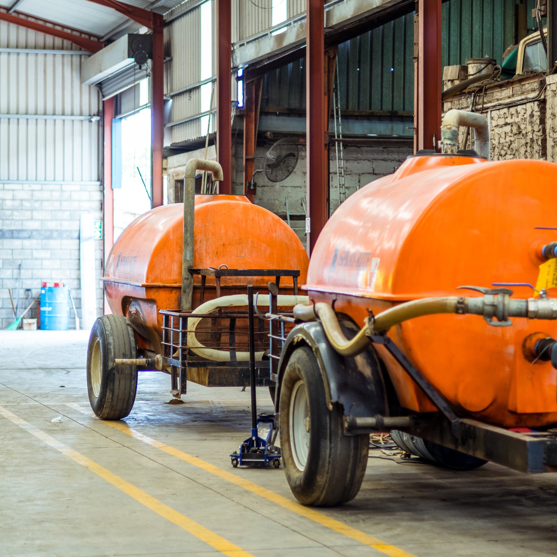 Two orange Spray-Rite tanker trailers parked inside the Turn-Rite workshop