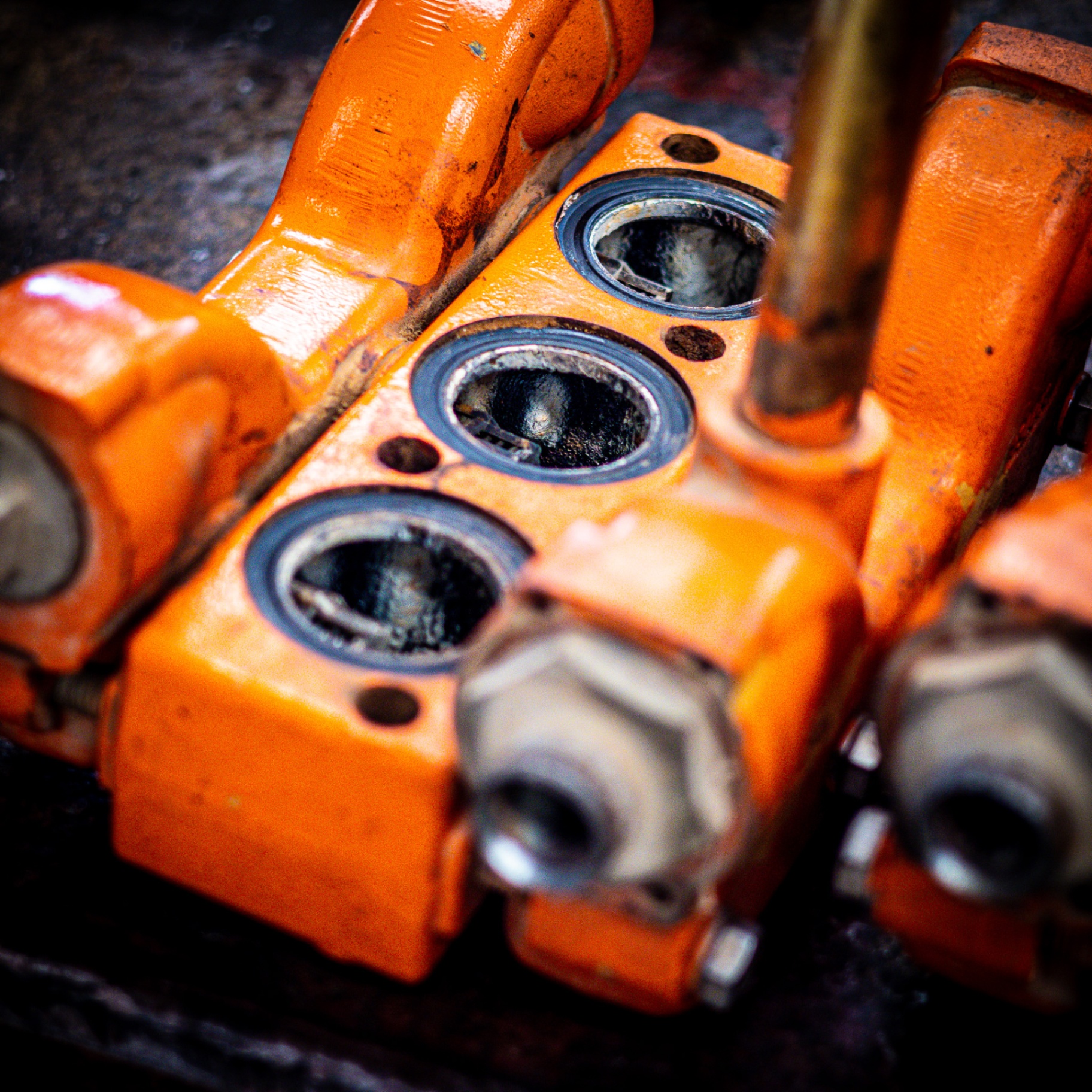 Close-up of orange hydraulic valve block with multiple ports