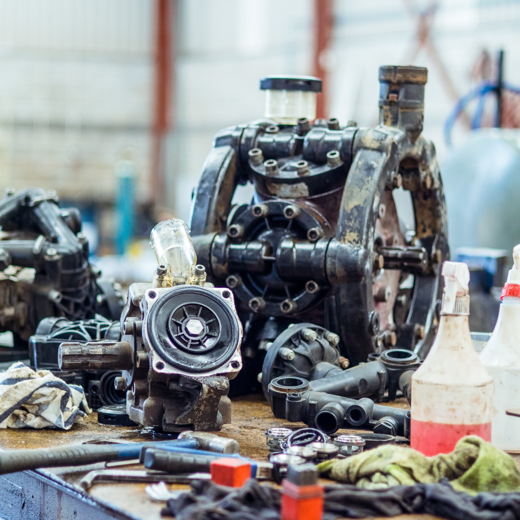 Workbench with disassembled diaphragm pumps and spray components being serviced